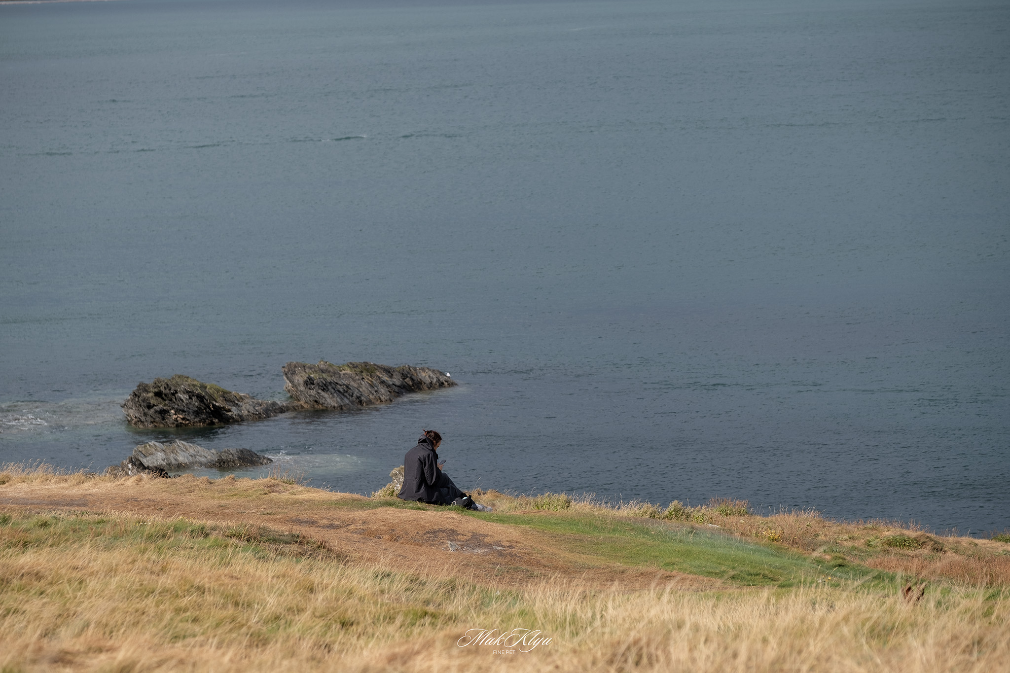 A person sits quietly near the water.